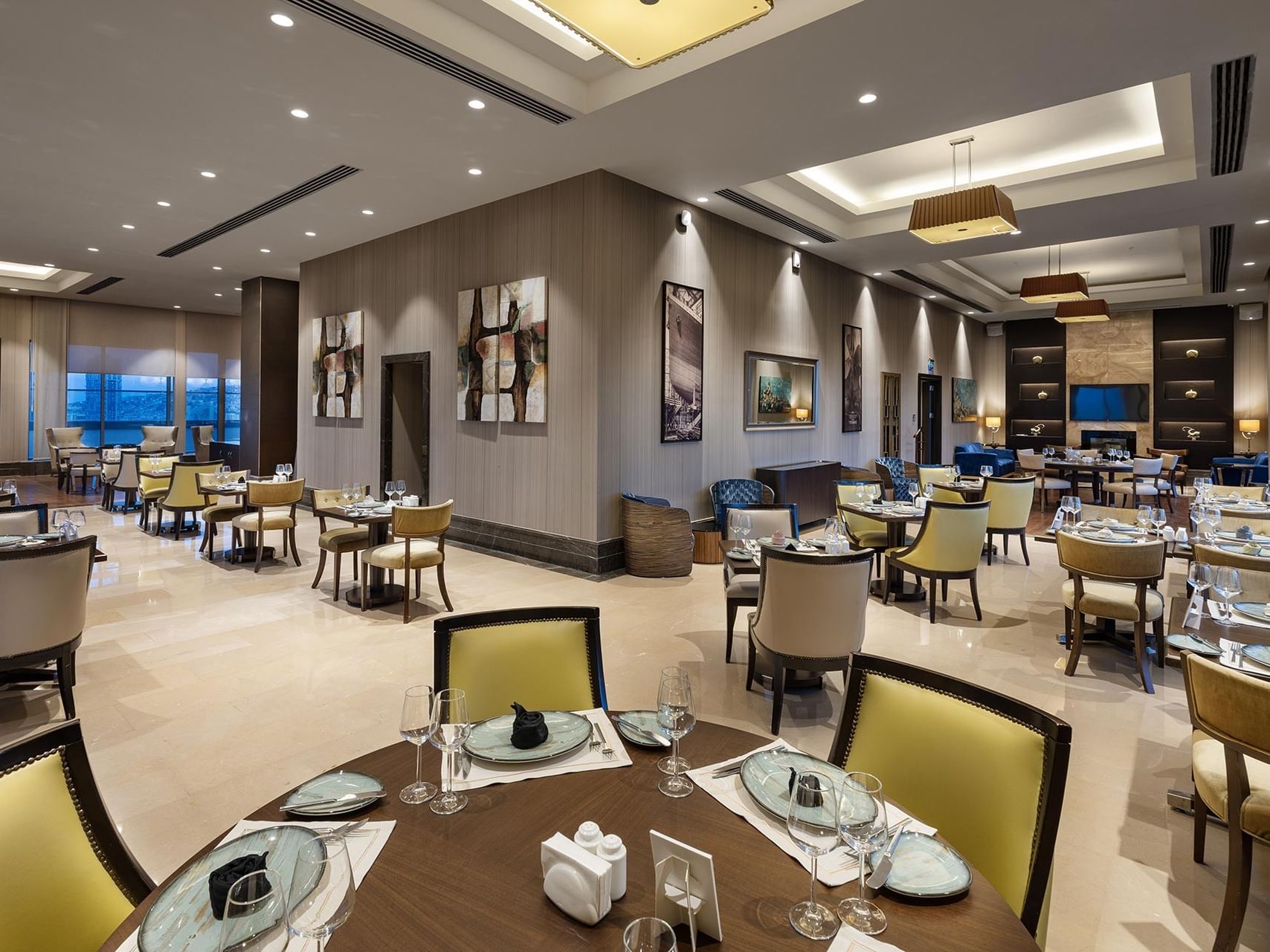  Compass Restaurant with round tables, yellow chairs, and artwork on the walls in Titanic Business Kartal.