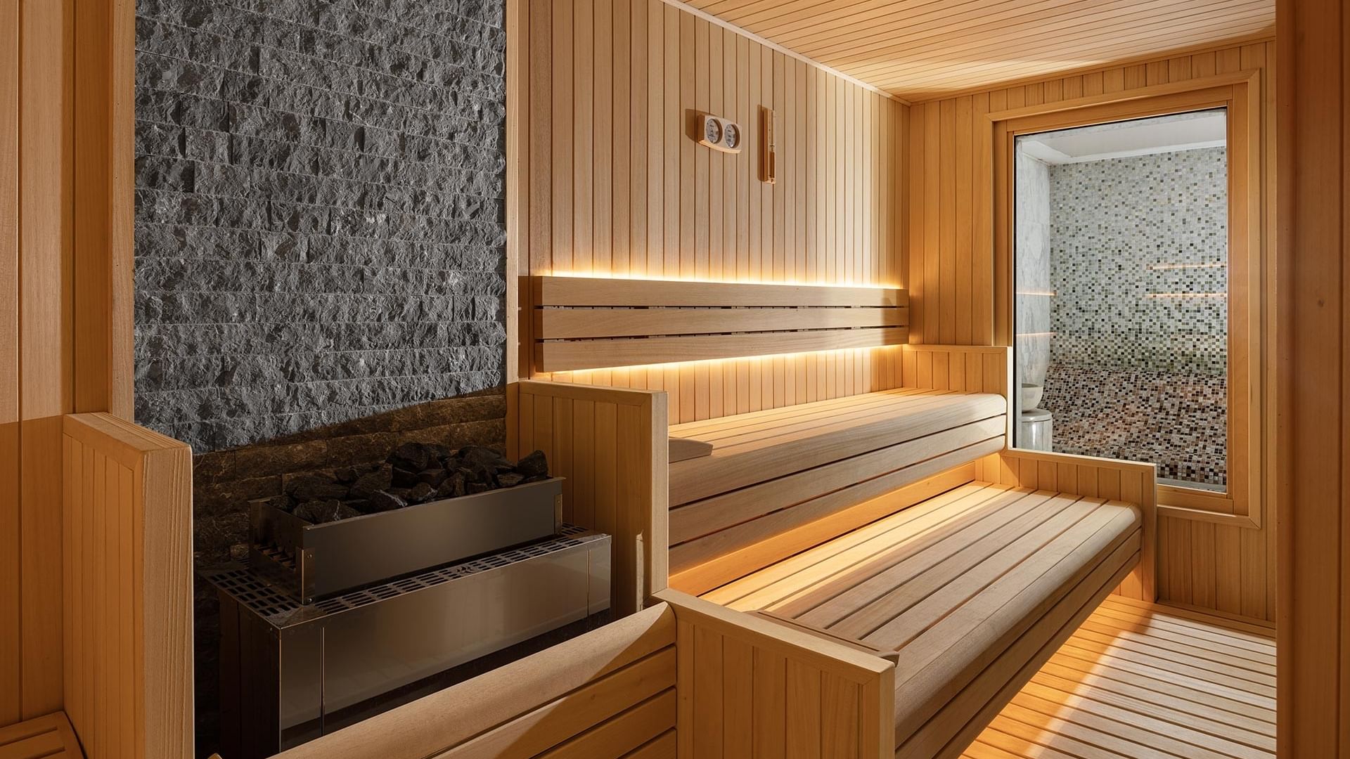 Wooden spa area with stone wall and benches at Titanic Business Kartal in Istanbul.