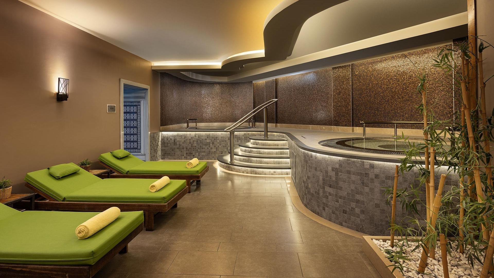 Modern spa lounge with green couches and a hot tub at Titanic Business Kartal in Istanbul.