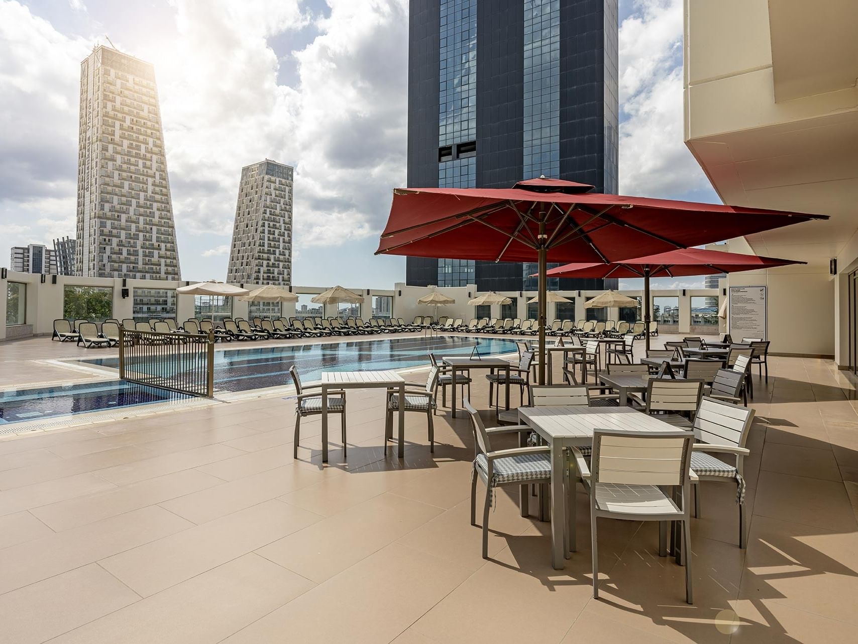 Outdoor pool area with tables, chairs, and red umbrellas in Befine Spa at Titanic Business Kartal.