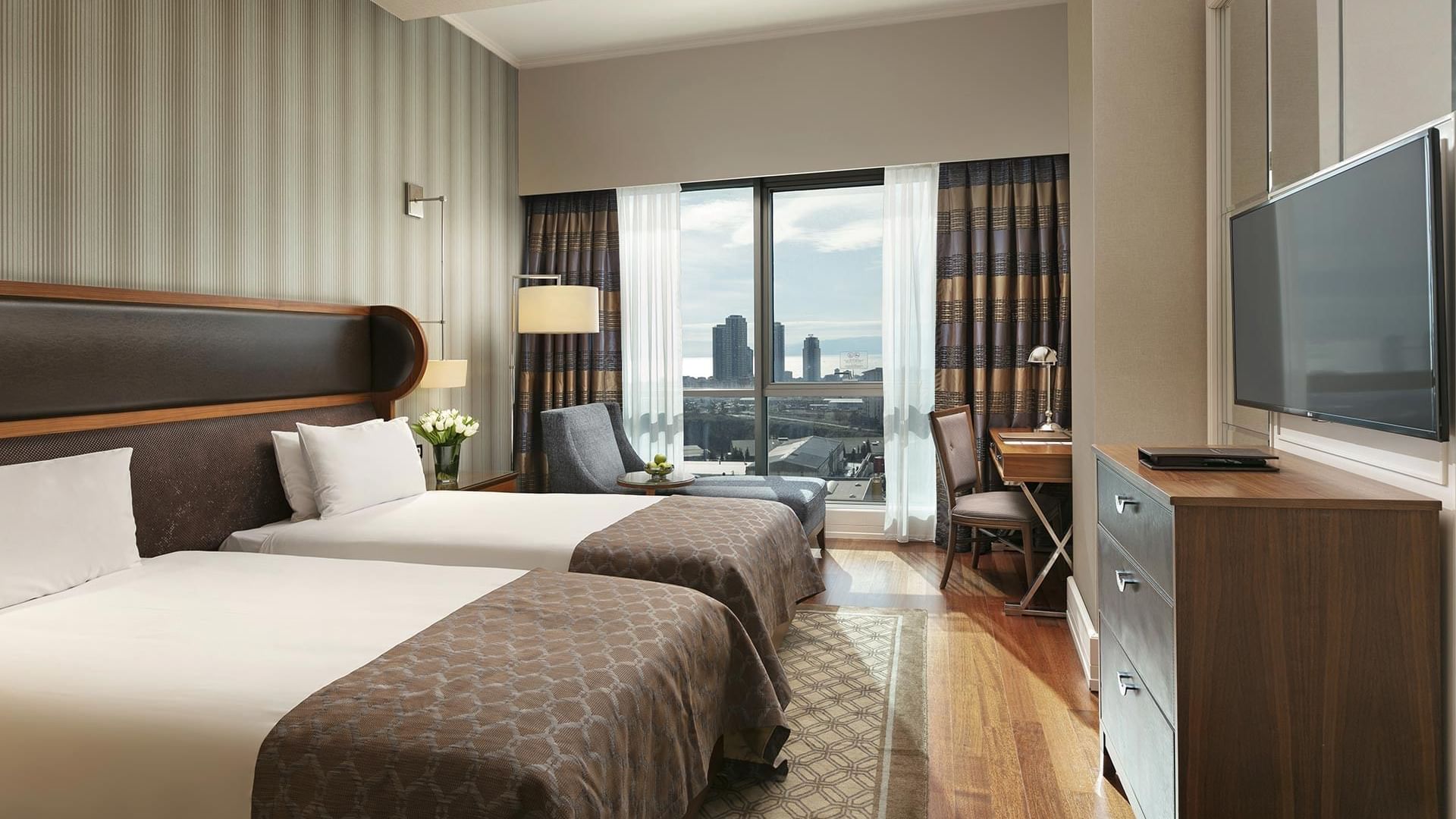 Two beds with cityscape view in Superior Room at Titanic Business Kartal, Istanbul.