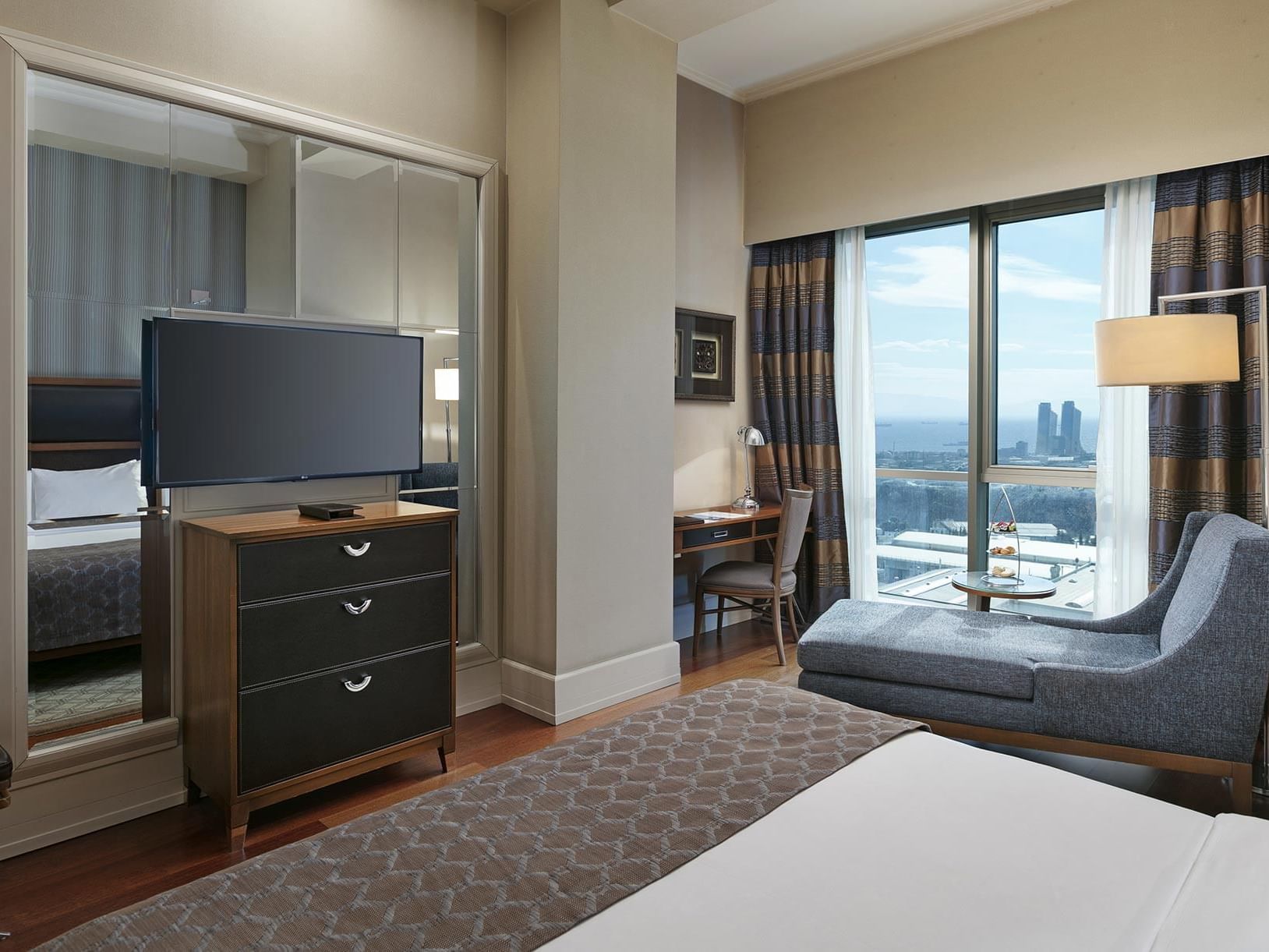 Interior of a luxurious hotel room with modern furniture and city view at Titanic Business Kartal.