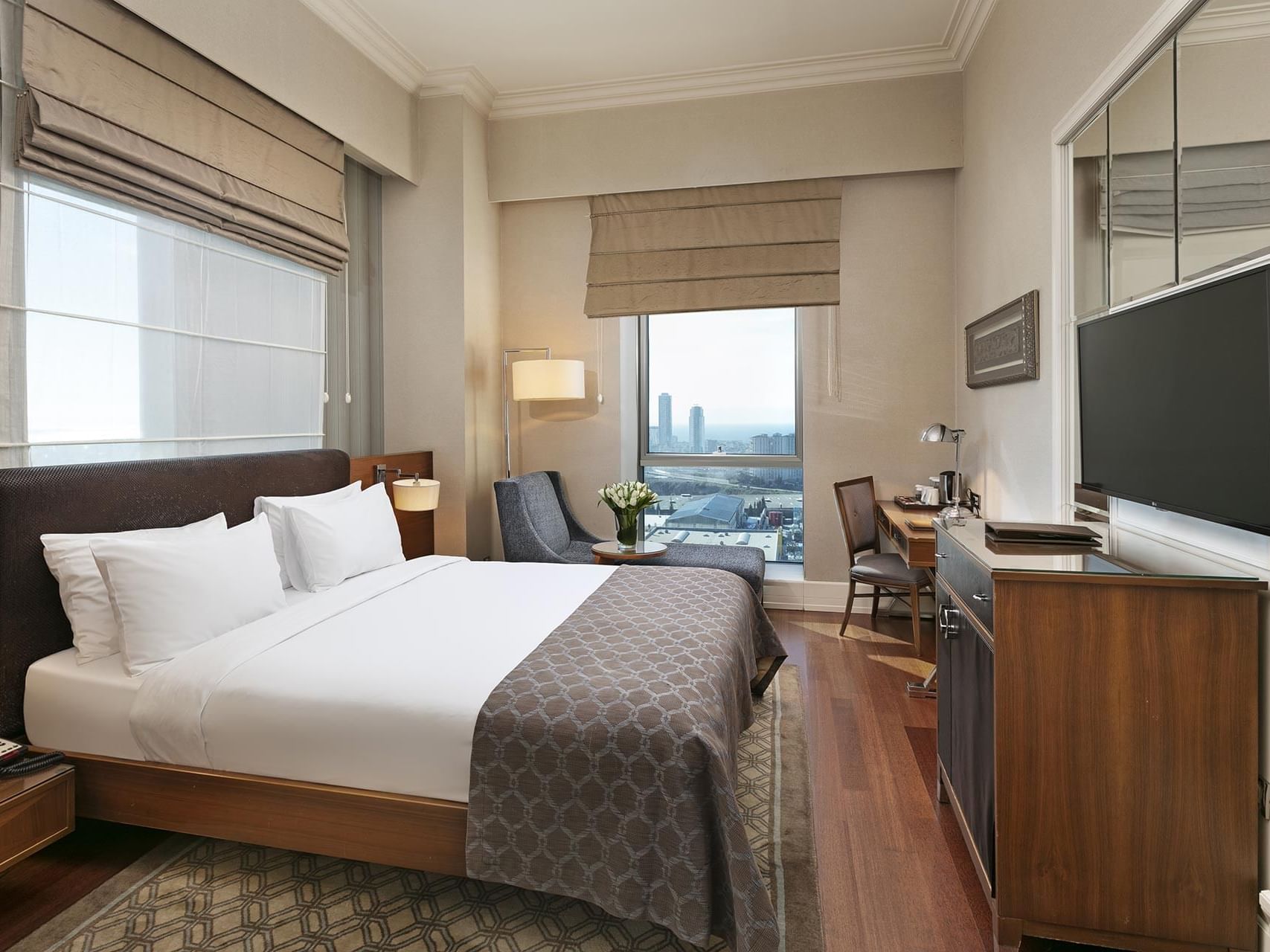 Elegant Deluxe Room with king-sized bed and city view at Titanic Business Kartal in Istanbul.
