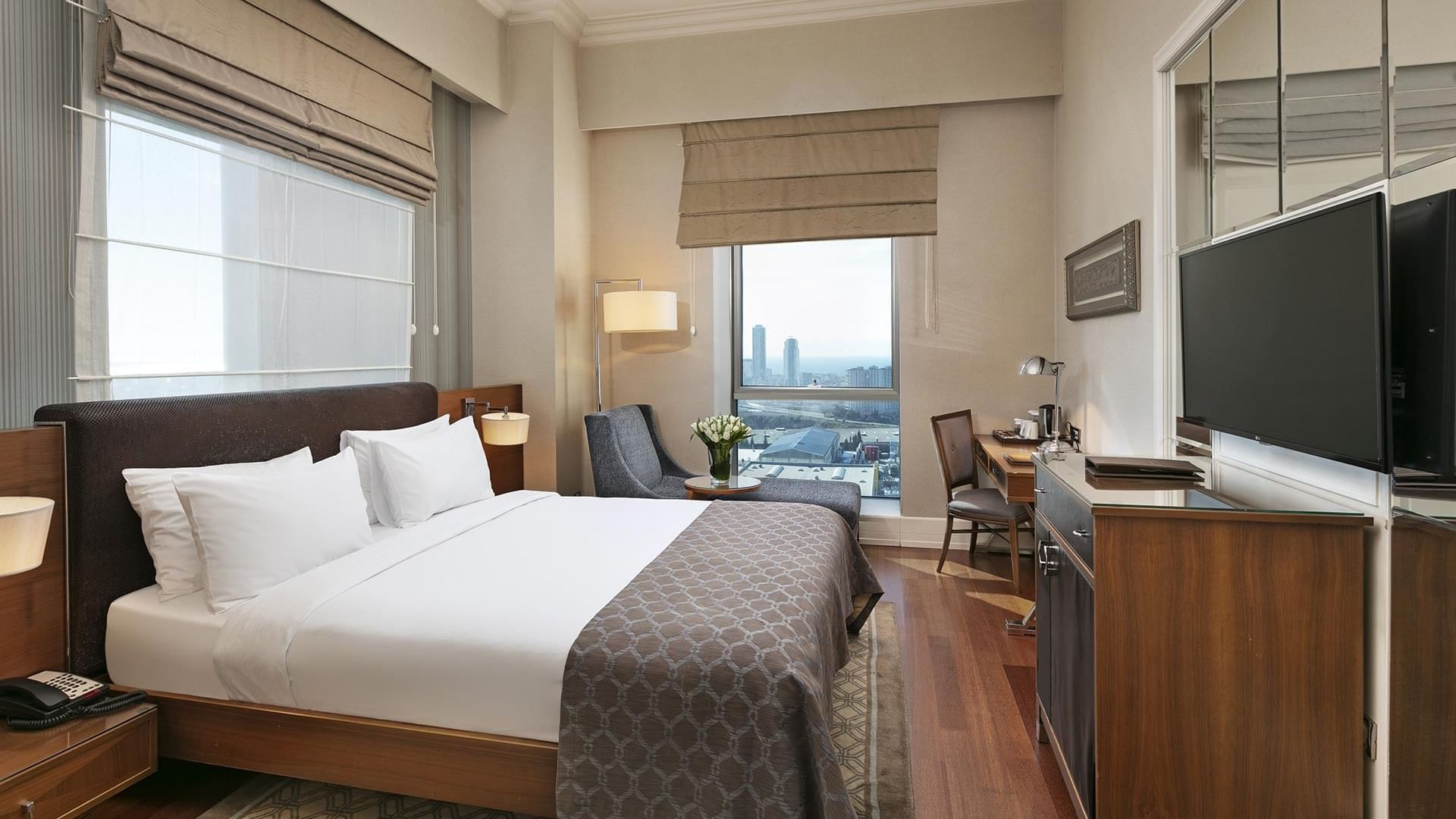 Elegant Deluxe Room with king-sized bed and city view at Titanic Business Kartal in Istanbul.