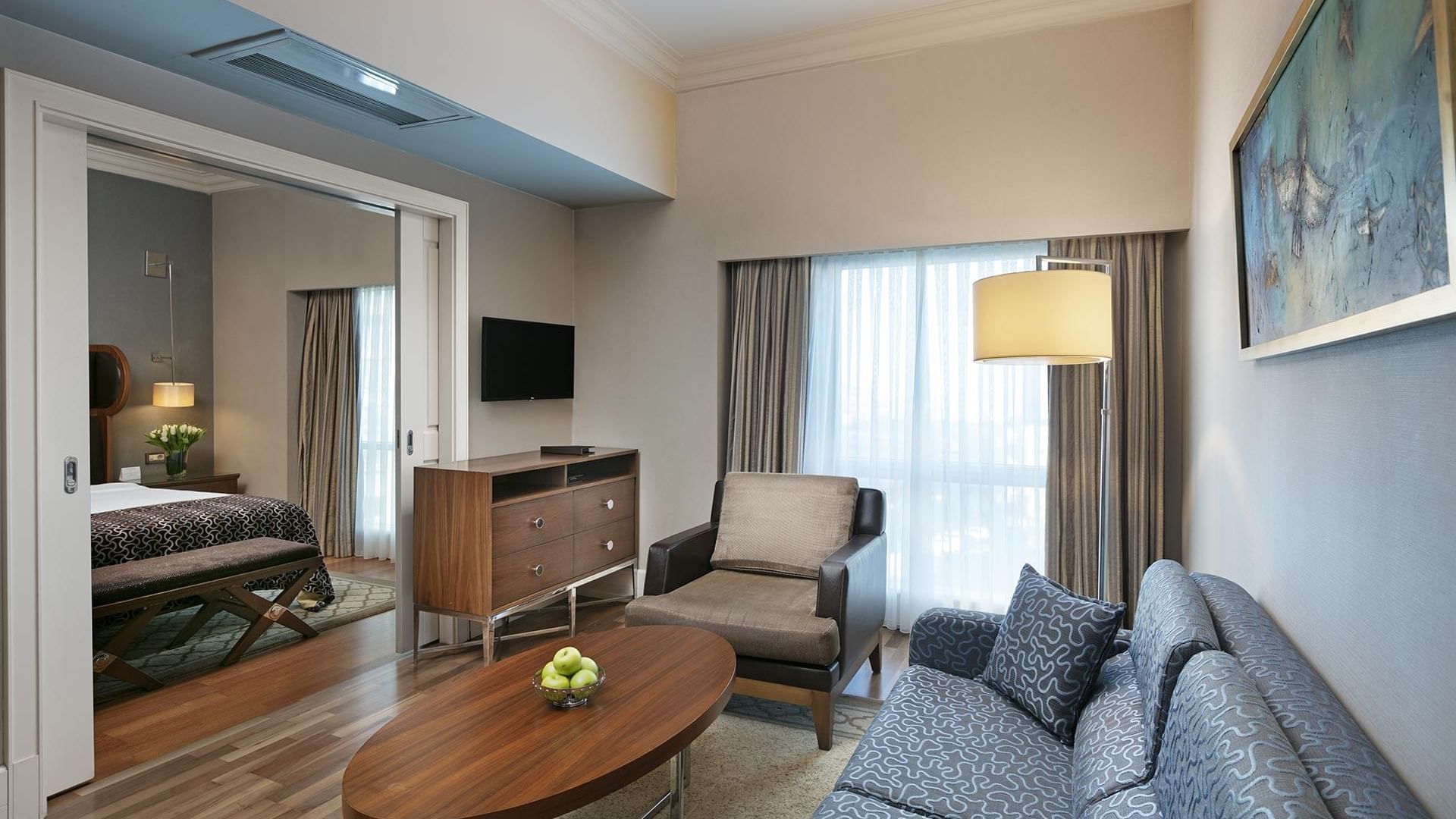 Elegant Club Suite living area with couch, chair, coffee table, and bedroom view at Titanic Business Kartal in Istanbul.