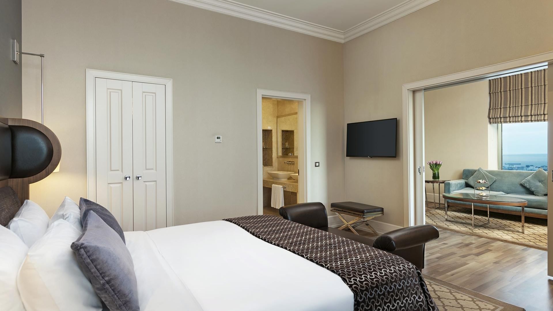 A luxurious Premier Suite at Titanic Business Kartal in Istanbul, featuring a king bed, seating area, and ocean view.