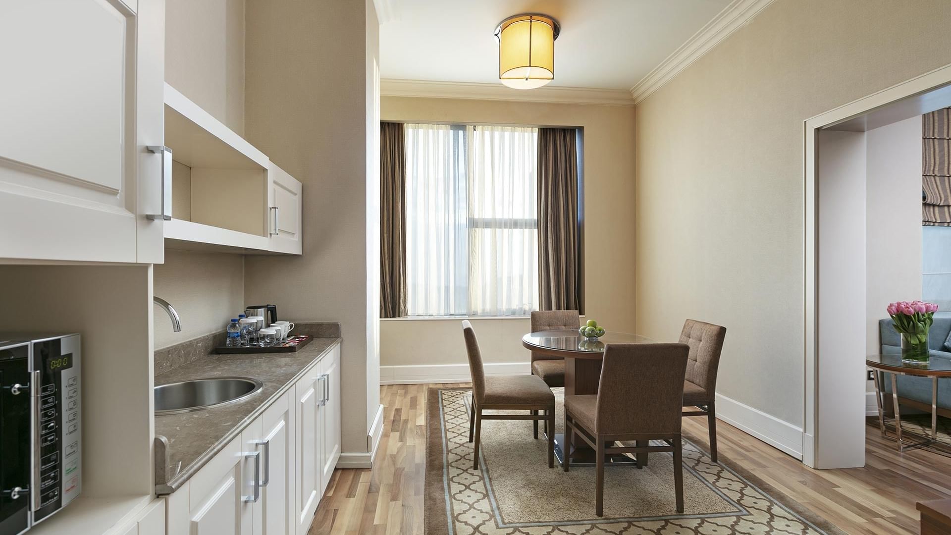 Elegant Premier Suite dining area with table, chairs, and kitchen at Titanic Business Kartal in Istanbul.