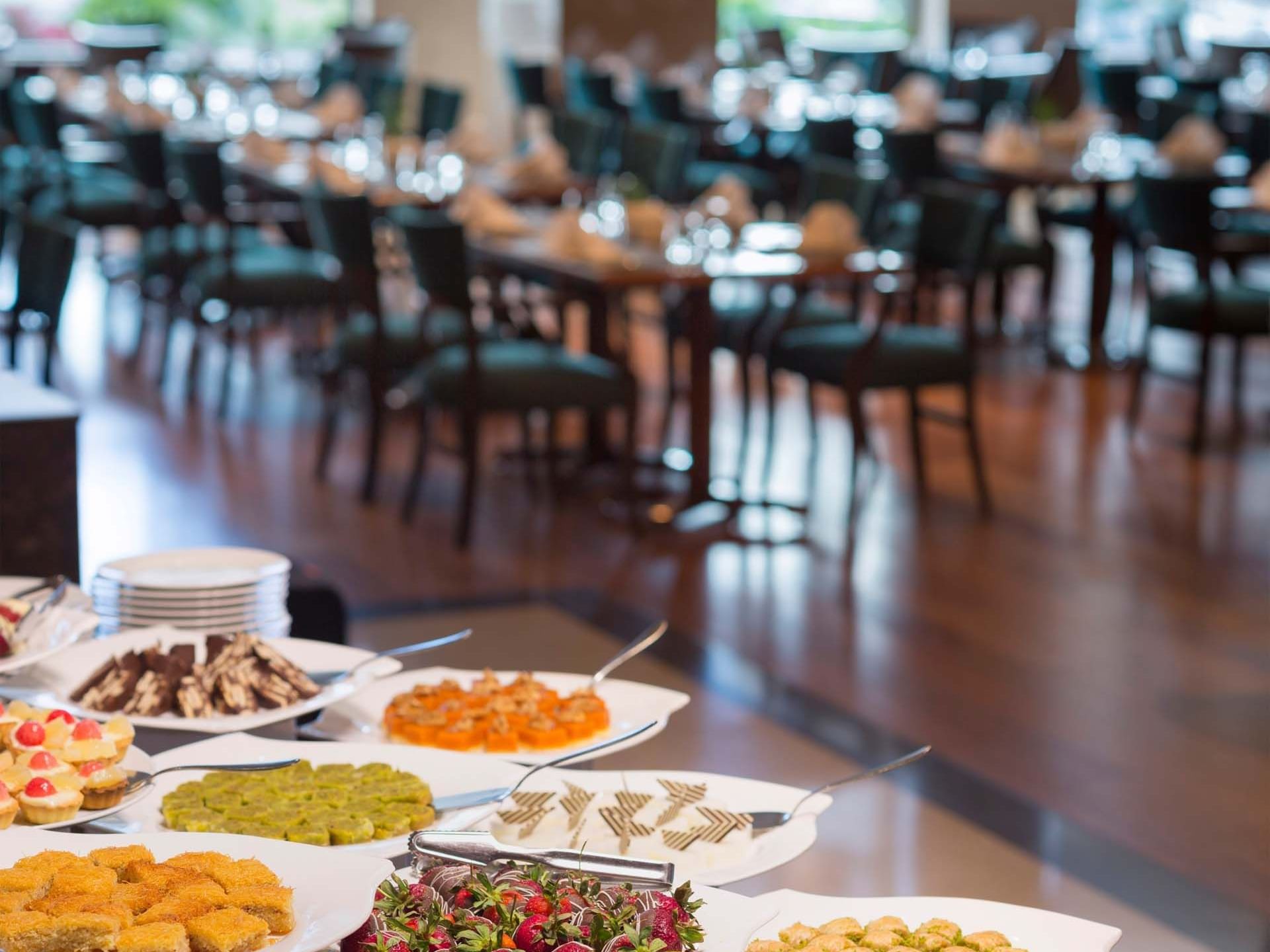 Various desserts on white plates with spoons in a dining area at Titanic Business Kartal.