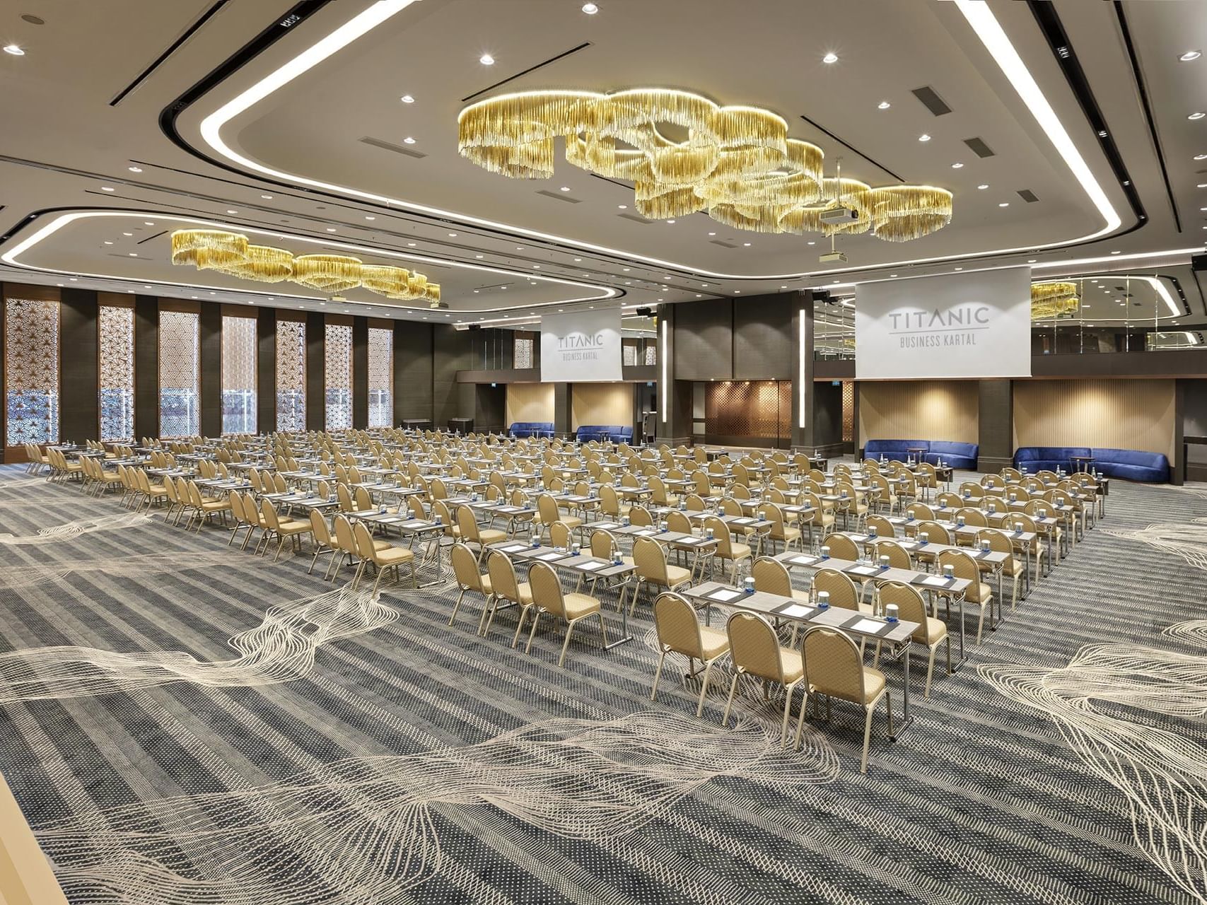 Titanic Business Kartal meeting room with rows of chairs and tables under a golden chandelier.