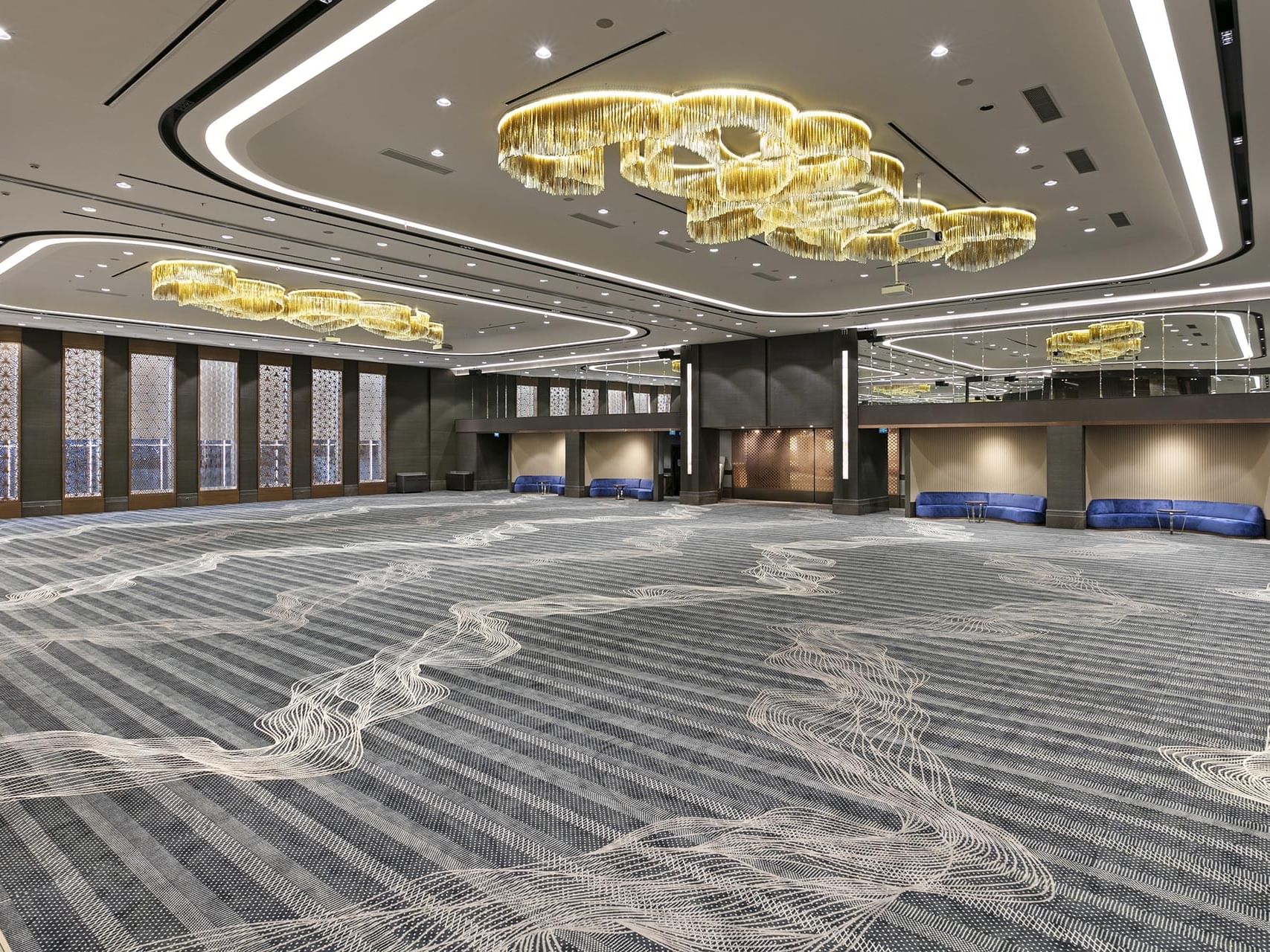 Spacious carpeted ballroom with intricate design and gold chandeliers at Titanic Business Kartal.