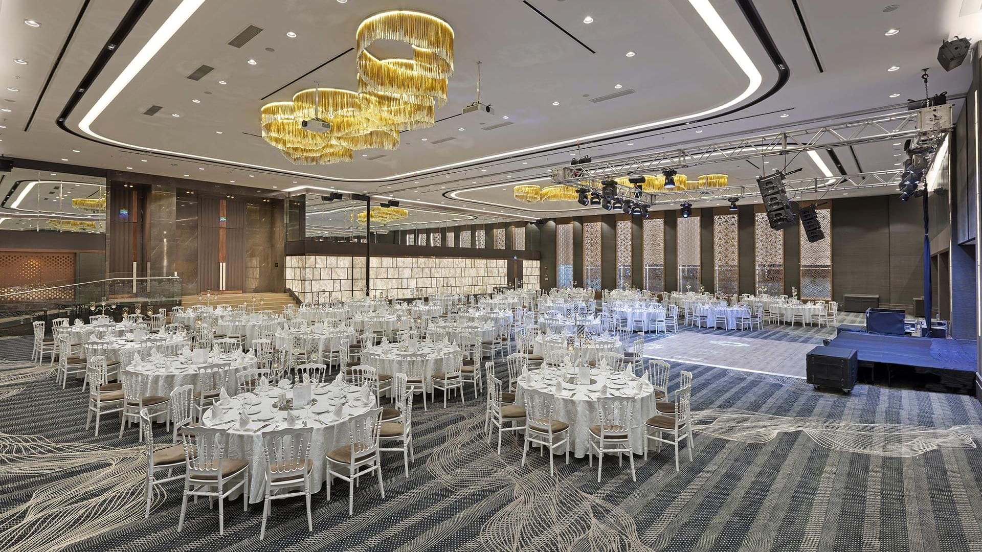 Elegant wedding setup with round tables and chandeliers in a large hall at Titanic Business Kartal, Istanbul.