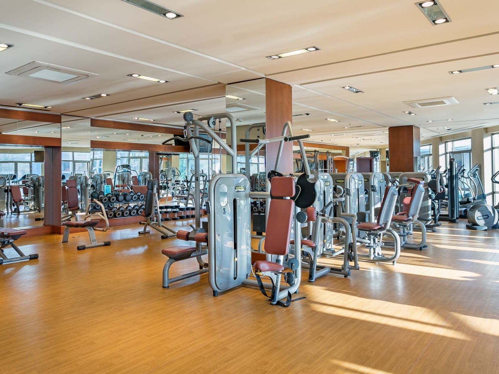 A well-equipped gym with various exercise machines and wooden flooring at Titanic Business Kartal.