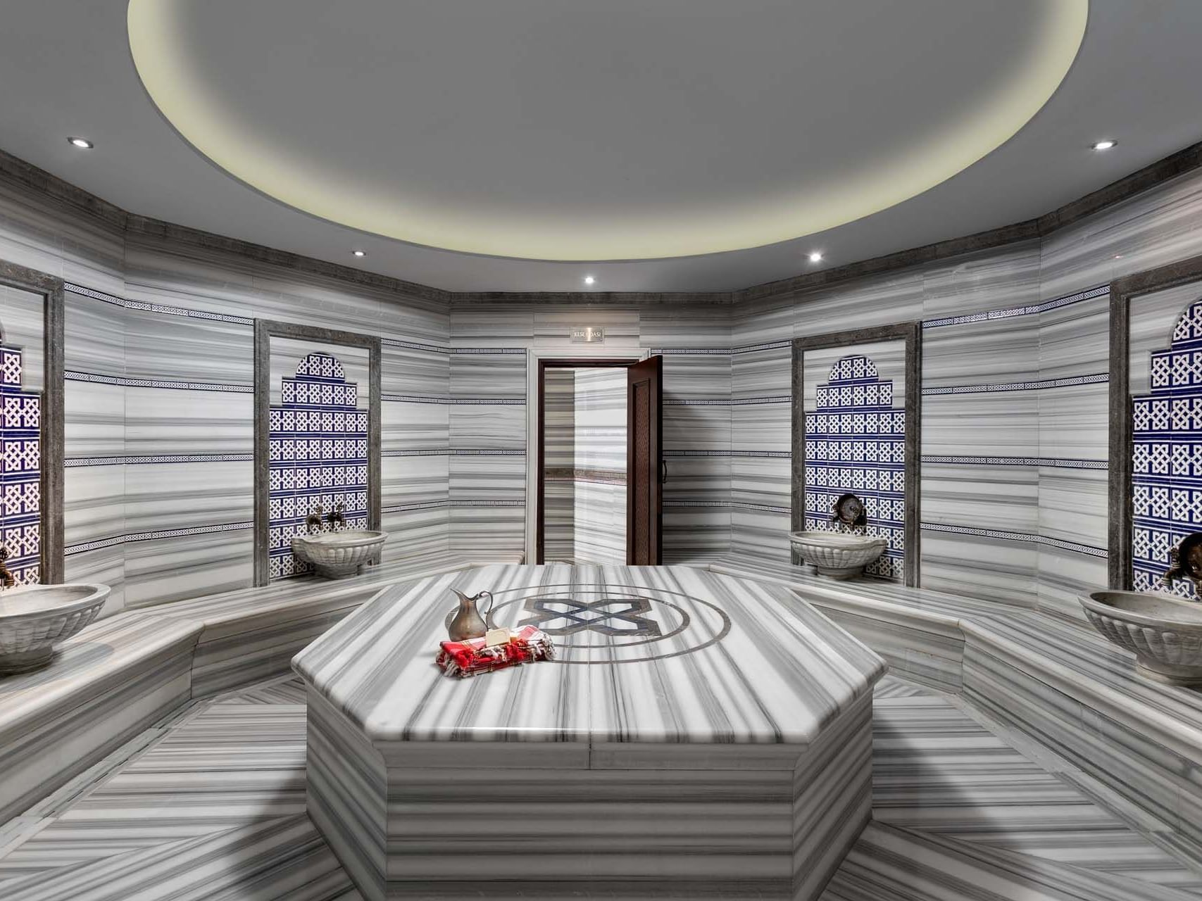 Luxurious Turkish bath room with a large central table and ornate marble walls at Titanic Business Kartal.