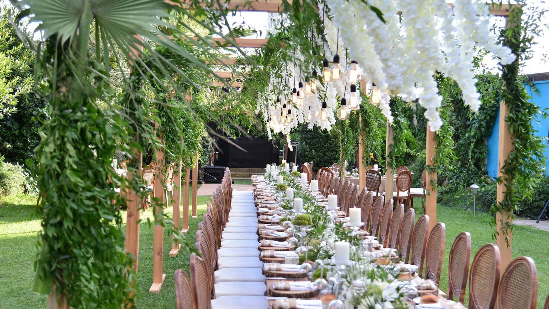 Elegant outdoor wedding reception setup with floral decorations and wooden tables at Titanic Business Kartal in Istanbul.