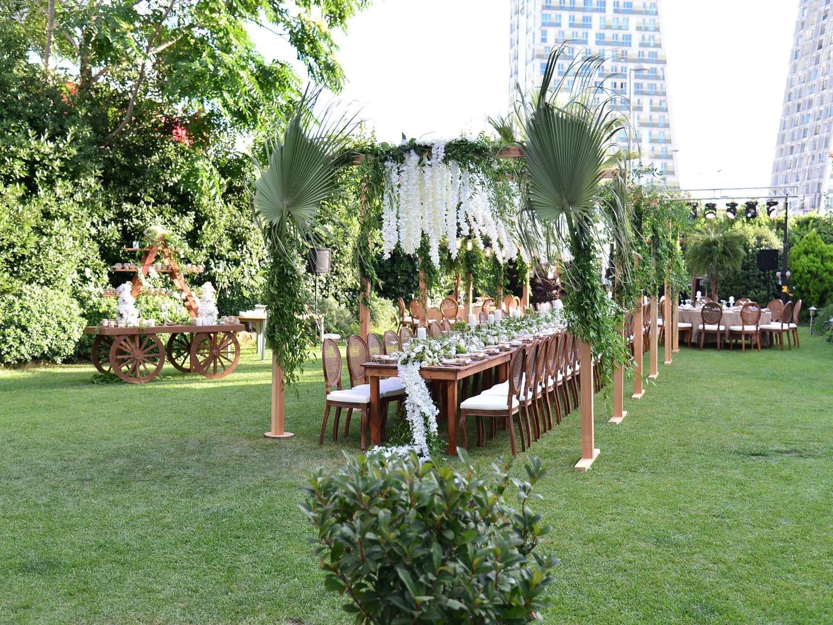 Outdoor banquet setting with long tables and chairs on a lawn at Titanic Business Kartal.