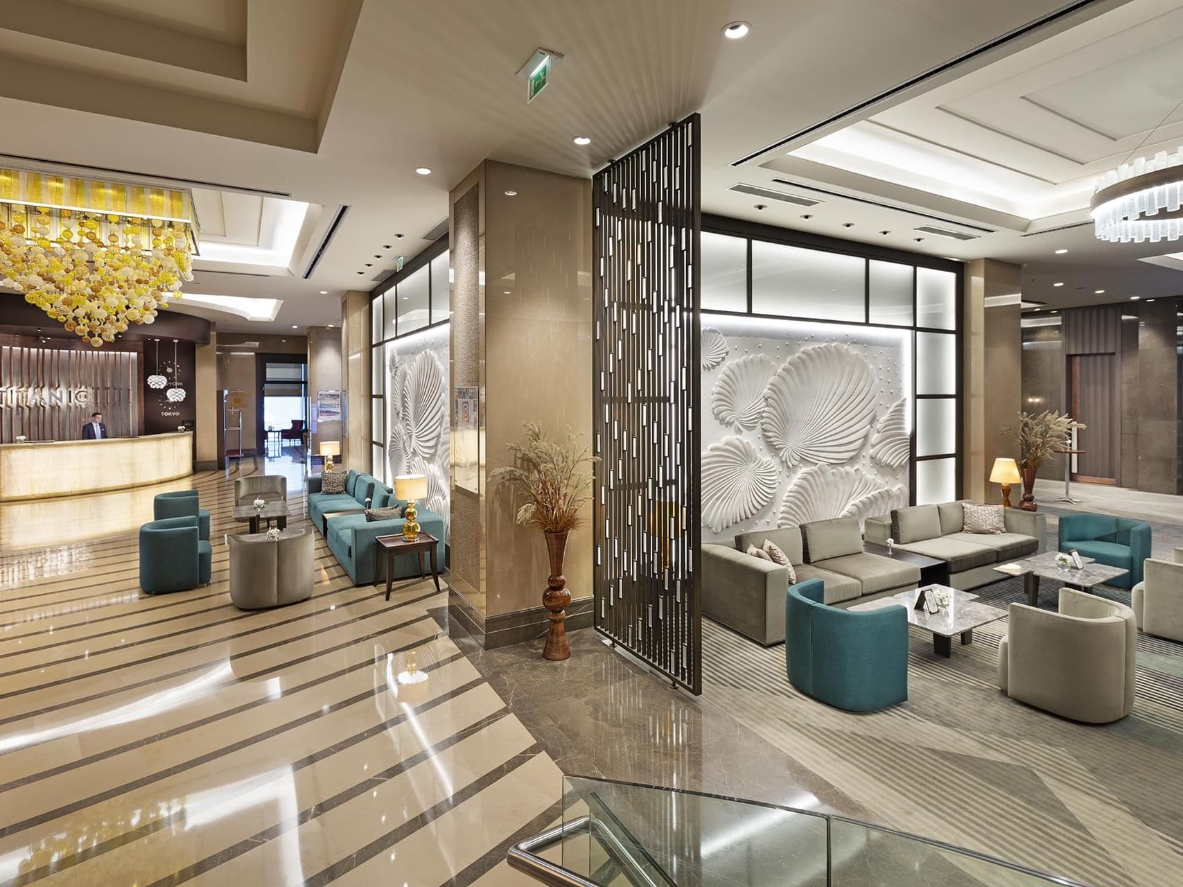A lobby area with lounge seating, a reception desk, and modern decor at Titanic Business Kartal.