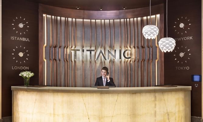 Hotel receptionist posing for a picture at the front desk of Titanic Business Kartal