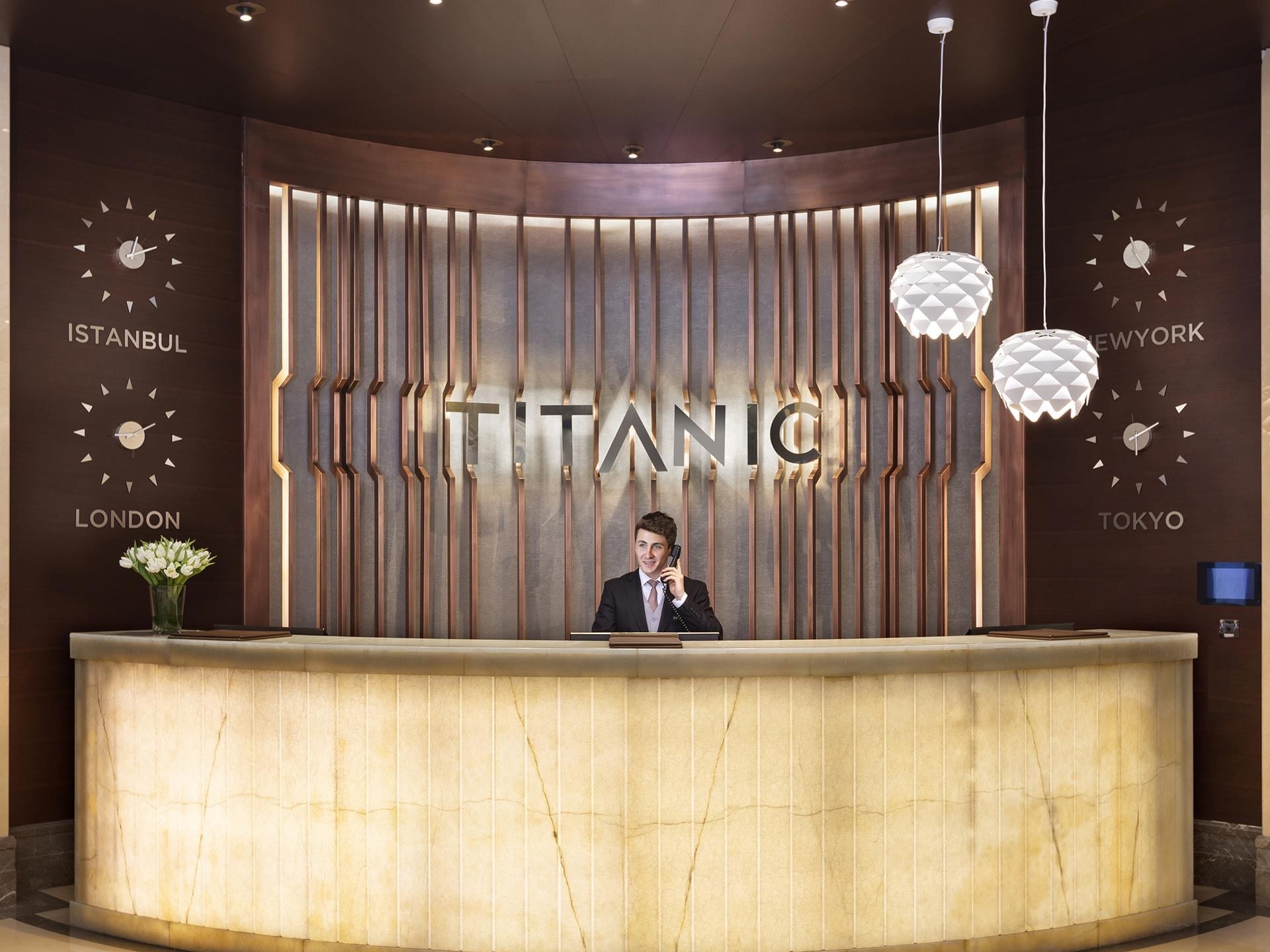 Reception area of Titanic Business Kartal hotel with a concierge on the phone.