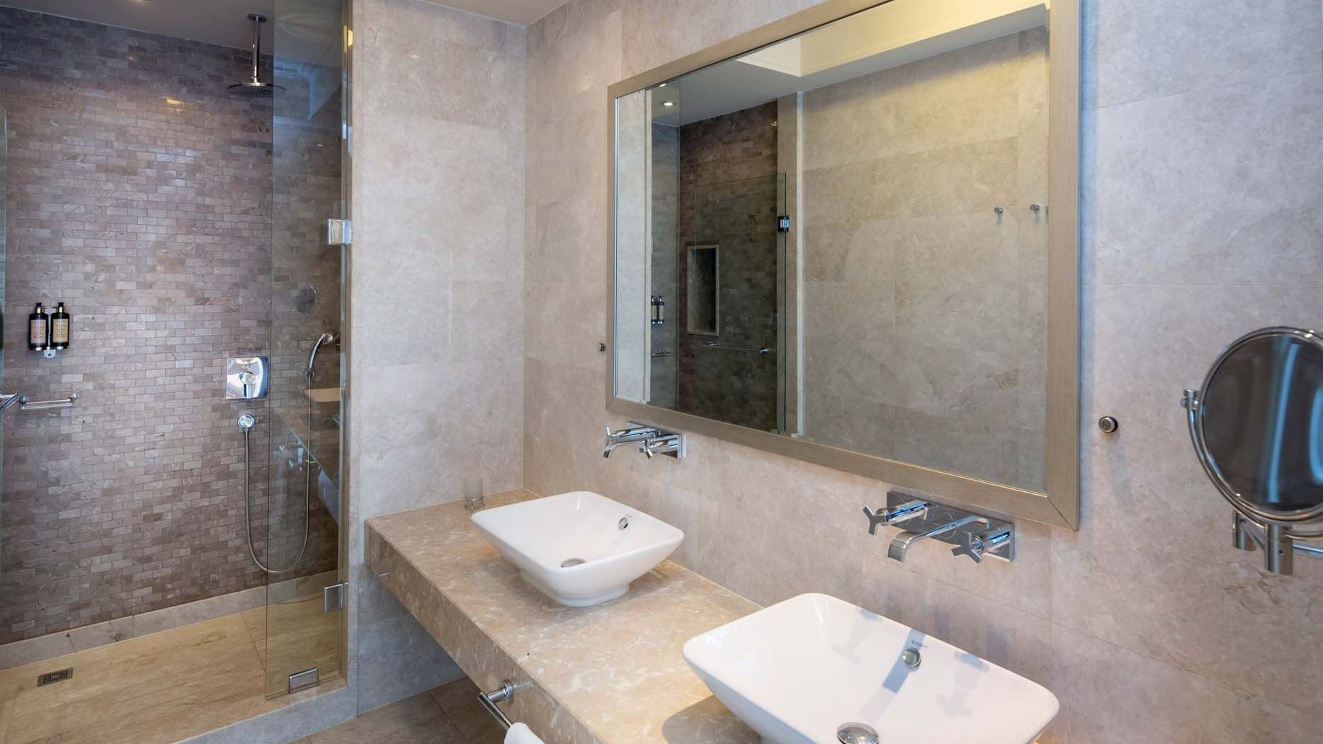 Modern bathroom with dual sinks, large mirror, and walk-in shower at Titanic Business Kartal in Istanbul.