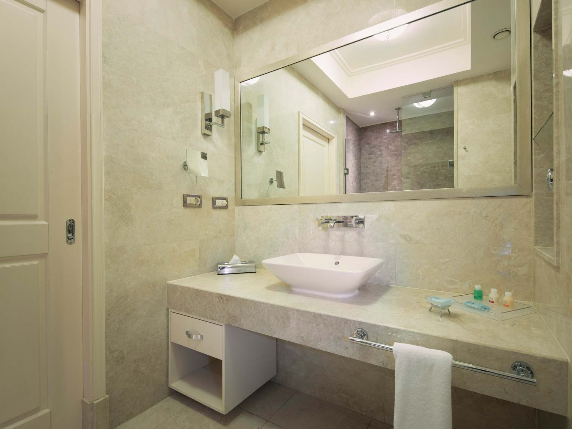 Modern bathroom with a large mirror, sink, and towel at Titanic Business Kartal.