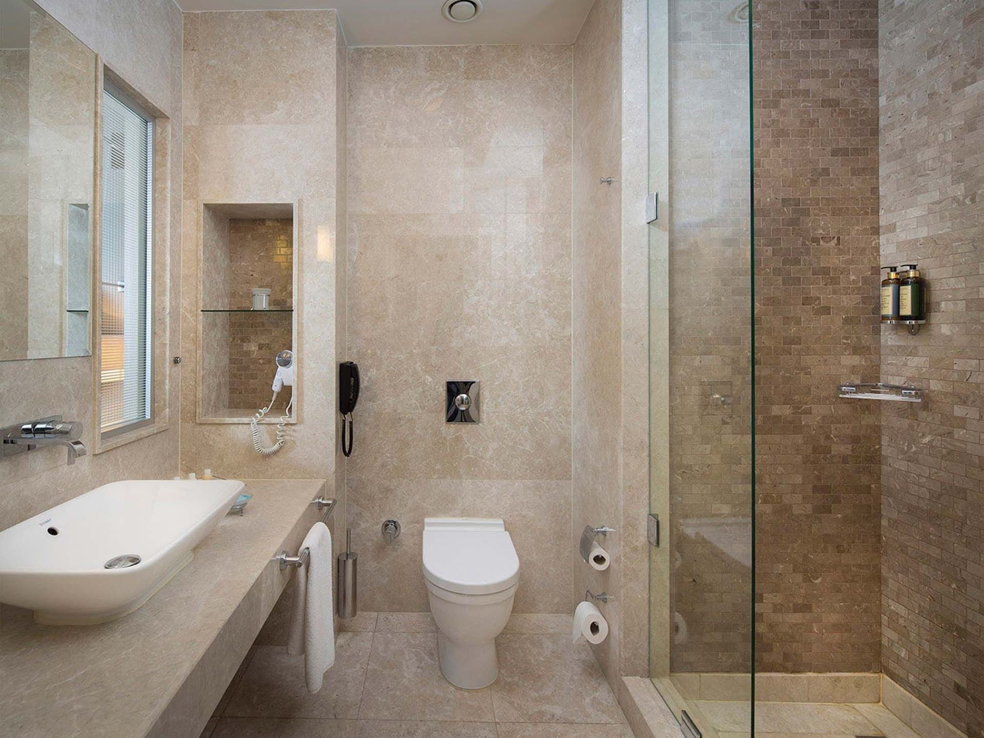 Modern bathroom with a large sink, toilet, and glass shower at Titanic Business Kartal.